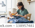 An adult woman using a domestic sewing machine, stitching denim fabric for clothing repair. Demonstrating hobby craft and design work 138957481