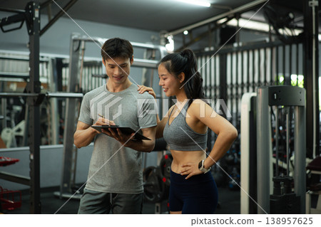 A personal trainer is discussing and reviewing physical progress with his female client. A personal trainer is discussing and reviewing physical progress with his female client. 138957625