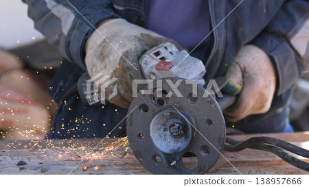 Closeup Hands Polishing Rusty Flange, Restorer Removing Corrosion With Angle Grinder, Gloves And Goggles, Sparks And Metal Dust Highlight Restoration Process On Cluttered Bench Closeup Hands Polishing Rusty Flange, Restorer Removing Corrosion With Angle Grinder, Gloves And Goggles, Sparks And Metal Dust Highlight Restoration Process On Cluttered Bench 138957666