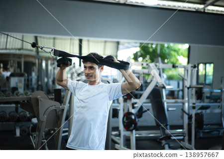 Man training shoulders with cable strap in a gym Man training shoulders with cable strap in a gym 138957667