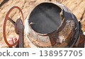 Rusty Concrete Mixer Drum With Steam. Close Up Of Flaking Paint And Corroded Metal, Red Handwheel Valve Visible, Sunlit Dusty Ground In Background, Tactile Industrial Texture, Abandoned 138957705