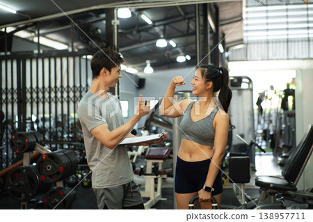 A personal trainer is discussing and reviewing physical progress with his female client. 138957711