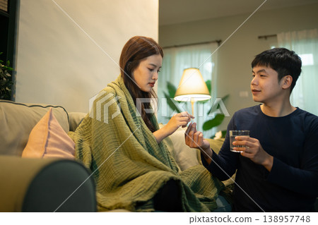 Man giving medicine to sick woman resting on sofa at home Man giving medicine to sick woman resting on sofa at home 138957748
