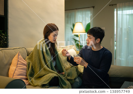 Man giving medicine to sick woman resting on sofa at home Man giving medicine to sick woman resting on sofa at home 138957749