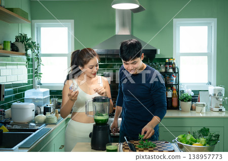 Happy couple blending green smoothie together at home Happy couple blending green smoothie together at home 138957773