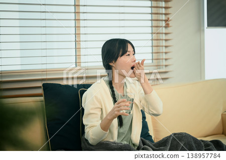 Woman taking medicine at home on sofa Woman taking medicine at home on sofa 138957784