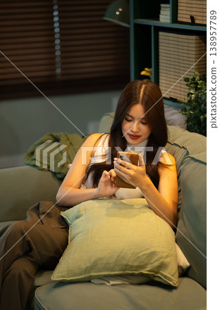 Young woman browsing on smartphone while sitting comfortably on sofa at home 138957789