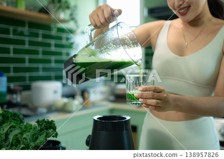 Closeup sporty woman pouring green smoothie in modern kitchen 138957826