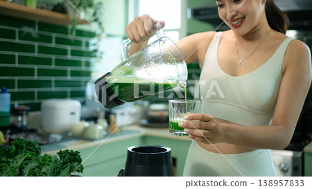 Closeup sporty woman pouring green smoothie in modern kitchen 138957833