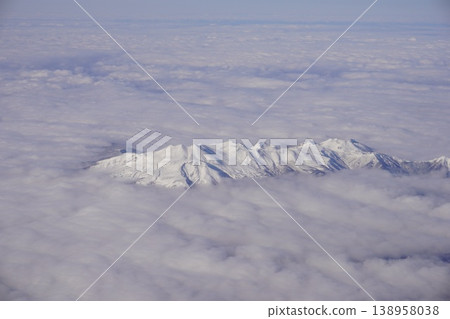 Aerial photograph of multiple peaks floating in a sea of clouds in the Yatsugatake Mountains during winter, taken from an airplane. Aerial photograph of multiple peaks floating in a sea of clouds in the Yatsugatake Mountains during winter, taken from an airplane. 138958038