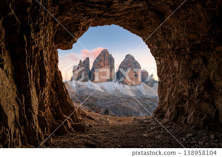 Grotta delle Tre Cime rocky tunnel framing sunset view of Tre Cime di Lavaredo mountain peak in Dolomites, Italy 138958104