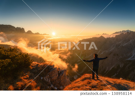 Majestic view of male tourist standing with sunrise over mountain ridge in Cadini di Misurina, Dolomites, Italy Majestic view of male tourist standing with sunrise over mountain ridge in Cadini di Misurina, Dolomites, Italy 138958114