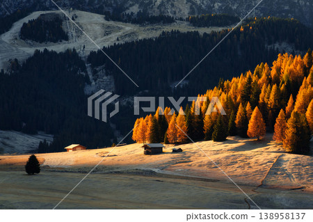 Sunrise over Alpe di Siusi with wooden huts on rolling hill in autumn pine forest at Dolomites, Italy Sunrise over Alpe di Siusi with wooden huts on rolling hill in autumn pine forest at Dolomites, Italy 138958137