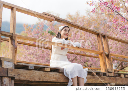 Relaxed woman sitting on wooden bridge during Wild Himalayan Cherry blooming in Khun Wang, Chiang Mai Relaxed woman sitting on wooden bridge during Wild Himalayan Cherry blooming in Khun Wang, Chiang Mai 138958255