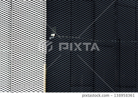 Abstract geometric modern perforated metal mesh facade featuring high contrast and security camera 138958361