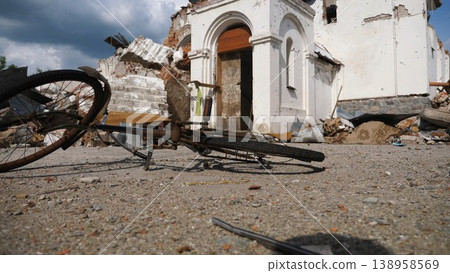 View to burned bike against the background of destroyed church at Kharkivska oblast. Ruined building after bomb attacks on ukrainian territory from russia army. russian invasion of Ukraine. Slow 138958569