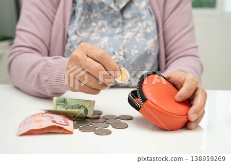 Asian senior or elderly old lady woman holding counting coin money in bag. Poverty, saving problem in retirement. 138959269