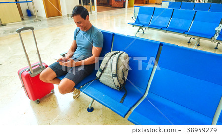 Traveler checking phone while waiting at airport terminal Traveler checking phone while waiting at airport terminal 138959279