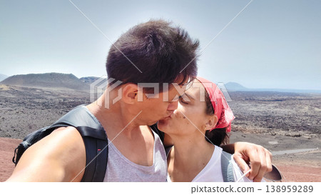Couple kissing during hike in volcanic Timanfaya National Park Couple kissing during hike in volcanic Timanfaya National Park 138959289