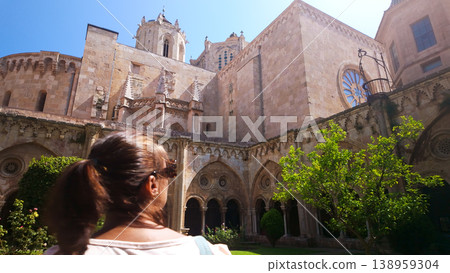 Woman viewing ancient Romanesque and Gothic cloister courtyard Woman viewing ancient Romanesque and Gothic cloister courtyard 138959304