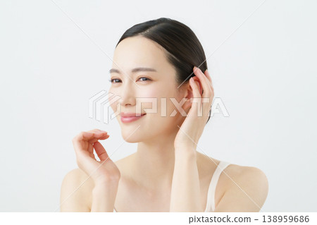A young Japanese woman smiling and touching her head against a white background. A young Japanese woman smiling and touching her head against a white background. 138959686
