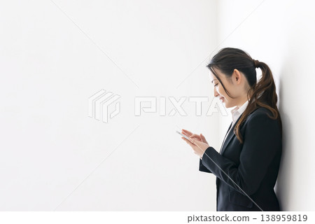 Smiling business woman operating a smartphone Smiling business woman operating a smartphone 138959819