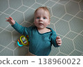 Little baby lying on soft play mat and reaching for colorful toy, top view perspective, curiosity and early childhood development concept. 138960022
