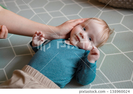 Loving mother's hands gently cradling her baby boy's head Loving mother's hands gently cradling her baby boy's head 138960024