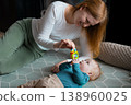 Happy mother playing with her infant baby boy on the floor at home 138960025