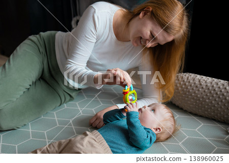 Happy mother playing with her infant baby boy on the floor at home 138960025