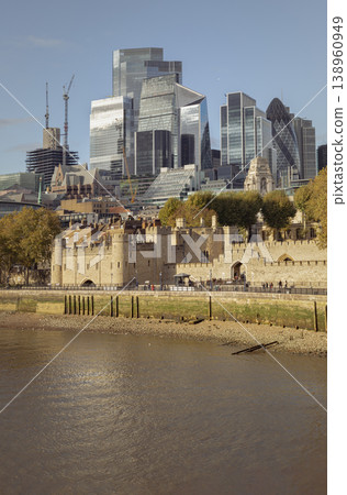 The weathered limestone of the Tower of London stands in silent vigil, anchoring a skyline of glass-crowned ambition. This historic fortress provides a tactile foundation for the gleaming vertical 138960949