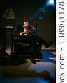 Elegant man in suit sitting relaxed with whiskey glass in moody cinematic lighting. 138961178