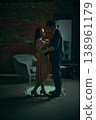 Couple standing close facing each other in emotional conversation in moody loft interior 138961179