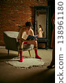 Man reading book in armchair ignoring woman reflected in mirror in loft interior. 138961180