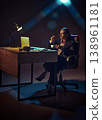 Business woman sitting at desk with coffee working late in dramatic office lighting. 138961181