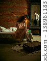 Sad woman sitting on bed looking down while man reflected in mirror in loft interior. 138961183
