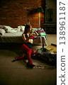Woman sitting on floor talking on vintage phone near suitcase in moody loft bedroom. 138961187