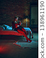 Young woman in red lingerie drinking wine sitting on bed in moody loft interior. 138961190