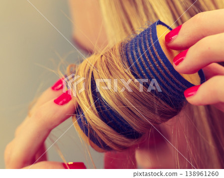Woman curling her hair using rollers Woman curling her hair using rollers 138961260