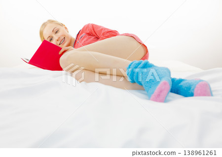 Woman relaxing in bed reading book Woman relaxing in bed reading book 138961261