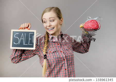 Woman holding shopping cart with brain and sale 138961345