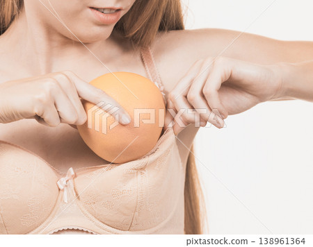 Woman small boobs puts big fruit in her bra 138961364
