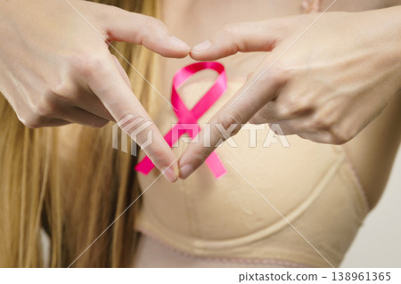 Woman with pink cancer ribbon on breast Woman with pink cancer ribbon on breast 138961365