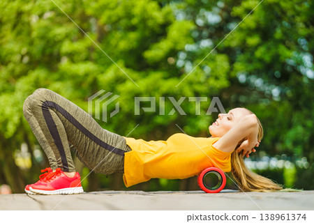 Girl doing exercises outdoor, using roller 138961374