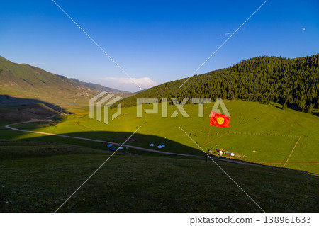 Kyrgyzstan green valley with yurts, grazing animals and national flag 138961633