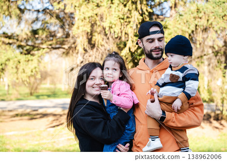 Family with mother father daughter and baby son standing in park holding children and showing different emotions. Concept of parenting and family interaction 138962006