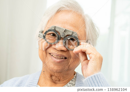 Optometrist checking Asian elderly woman ophthalmic vision eye test and using optical trial frame. 138962104