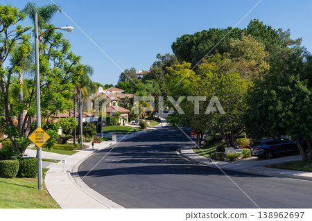 Quiet suburban street with green trees and modern houses 138962697