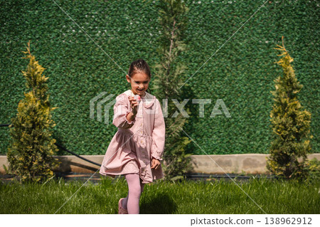 Little girl playing with a small object outdoors Little girl playing with a small object outdoors 138962912