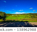 Panoramic view of a small town in a lush green valley at the foot of blue mountains. 138962988